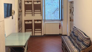 A room with a ceiling fan, a window with a view, a radiator, and a sofa. - House in Progress (Colle di Val d'Elsa)