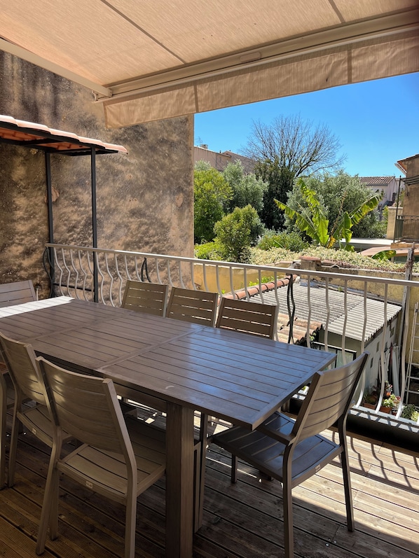 An outdoor patio with a table and chairs, a covered area, and a view of a garden and buildings. - T3 in the heart of the pedestrian zone, 2 steps from the port (Sanary-sur-Mer)