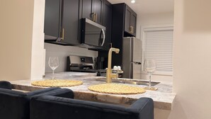A modern kitchen with dark cabinetry, a stainless steel refrigerator, a built-in microwave, and a gas stove. - The Prestige Long Beach/ On Site Free Parking (Long Beach)