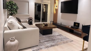 A modern living room with a sofa, coffee table, and a flat-screen TV mounted on the wall. - The Prestige Long Beach/ On Site Free Parking (Long Beach)