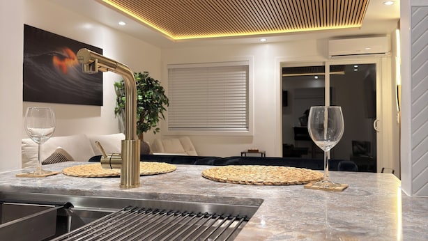 A modern kitchen with a marble countertop, a built-in sink, and a wooden ceiling with recessed lighting. - The Prestige Long Beach/ On Site Free Parking (Long Beach)