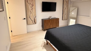 A bedroom with a bed, a TV, a dresser, and artwork on the walls. - The Prestige Long Beach/ On Site Free Parking (Long Beach)