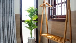 A corner with a wooden shelf, a potted plant, and a pair of blue flip-flops. - New Moon Villa (Hoi An)