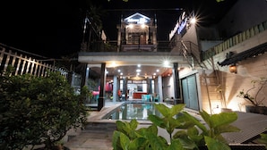 A hotel with a swimming pool, a covered outdoor area, and a staircase leading to the entrance. - New Moon Villa (Hoi An)