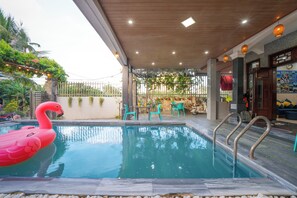 Una piscina al aire libre, sillones reclinables de piscina