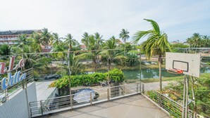 A basketball court with a chain-link fence, palm trees, and a body of water in the background. - New Moon Villa (Hoi An)