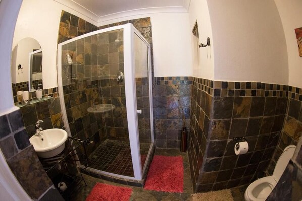 A bathroom with a glass-enclosed shower, a sink, and a toilet.