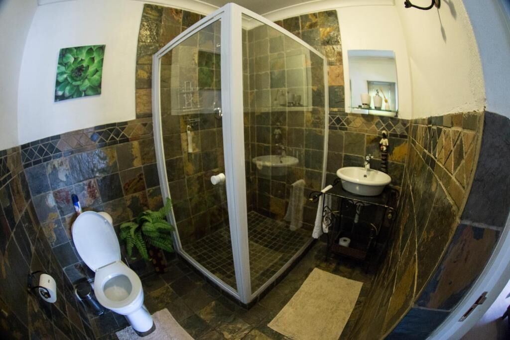 Un baño con ducha de vidrio, inodoro, lavabo y espejo.