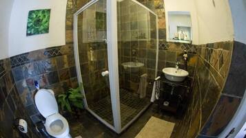 Un baño con ducha de vidrio, inodoro, lavabo y espejo.