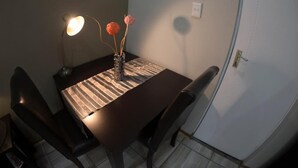 Een eettafel met stoelen, een lamp en een vaas met bloemen.