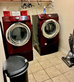 Two stacked front-loading washers, a trash bin, and a hose reel with clothes hangers. - Trunks up! Spacious 3-bd house close enough for fun,far enough for peace & quiet (Lancaster)