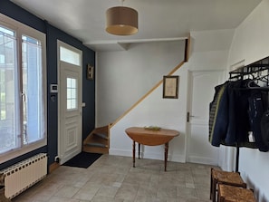 Ein Zimmer mit Treppe, Tisch, Heizkörper und Kleiderständer.