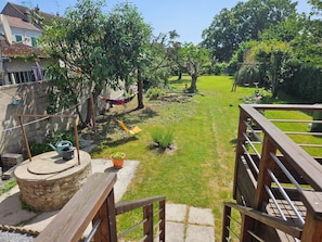 Ein Garten mit Hängematte, Stuhl, kleinem Gemüsegarten und einer Holzterrasse.