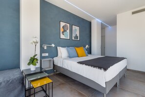 Ein modernes Schlafzimmer mit einem Bett, Nachttischen, einer Topfpflanze und abstrakter Wandkunst.