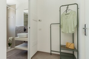 A bathroom with a white sink, a mirror, a towel rack with a striped towel, and a small plant. - Flamingo's Way: modern penthouse, large terrace, stunning view of sea and city (Cagliari)