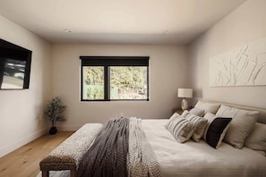 Ein Schlafzimmer mit einem Bett, einer Bank, einem Fenster und einer Wandleuchte.