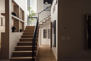 Eine Treppe führt zu einer zweiten Etage mit Blick auf den Himmel, einer Pflanze und einem Weinkühlschrank.
