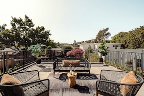 Eine Dachterrasse mit Gartenmöbeln, einem Holztisch und Topfpflanzen.