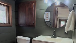 A bathroom with a toilet, sink, vanity, and a mirror. - The Remington House - Pet friendly, hot tub, and on ATV trails (Woodruff)