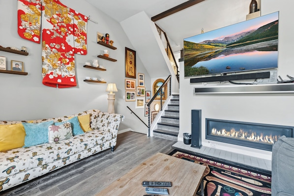 Ein Wohnzimmer mit Sofa, Kamin, Fernseher und einer Treppe.