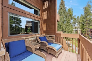 Eine Holzterrasse mit Korbmöbeln und einem großen Fenster.