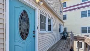 A house with a blue door, a wooden deck, and a window with a security screen. - Paxley`s: 2BR Spacious Beach Haven (Seaside Heights)