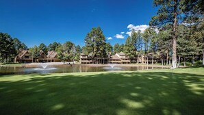 Un campo da golf con uno stagno, diversi edifici e alberi.