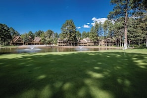 Ein Golfplatz mit Teich, mehreren Gebäuden und Bäumen.