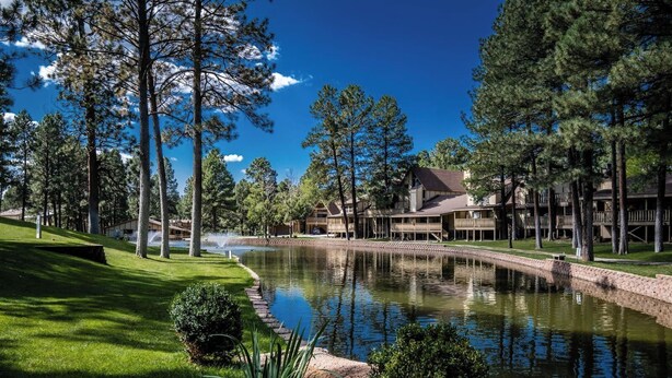 Un resort con uno stagno, un campo da golf e un edificio con diverse terrazze.