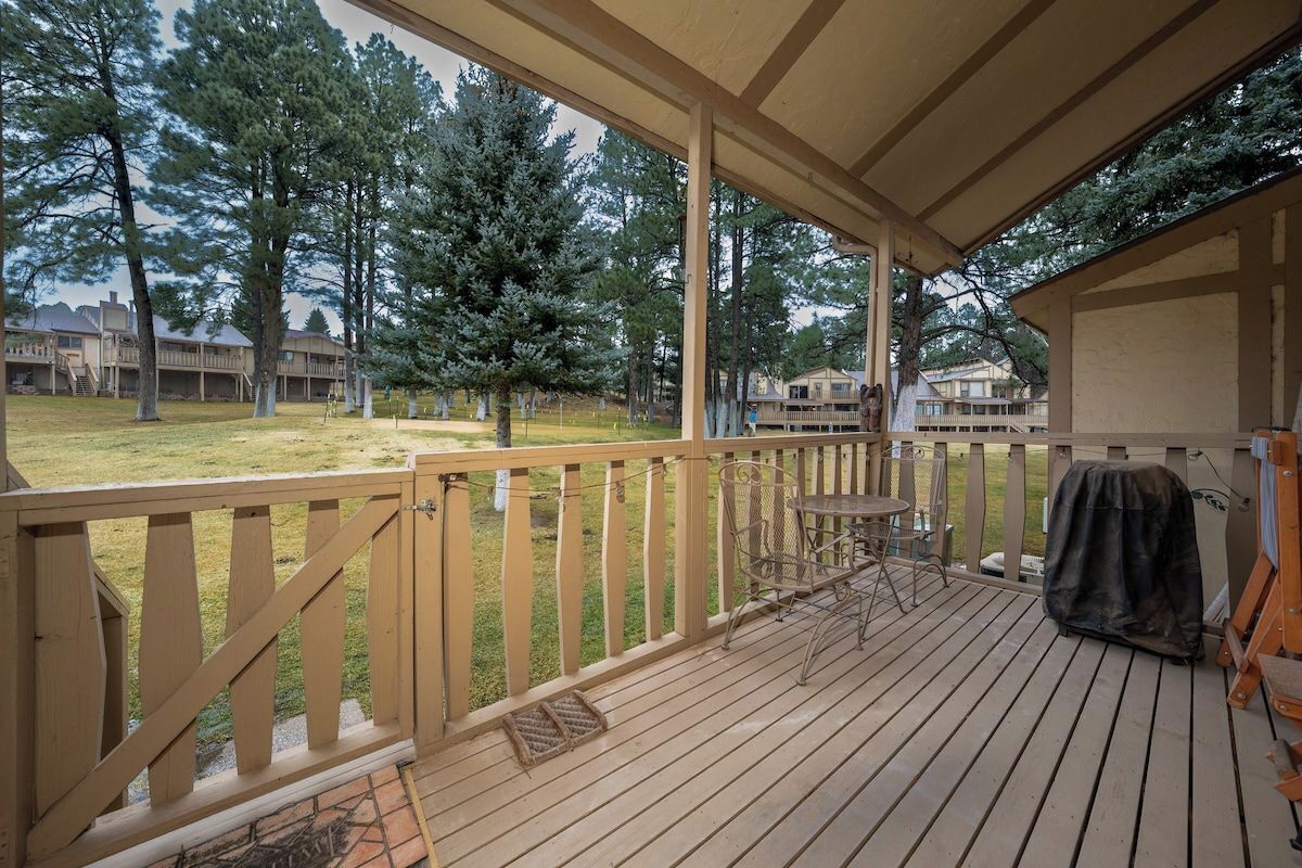 A wooden deck with a covered area, outdoor furniture, and a barbecue grill.