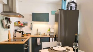 Une cuisine moderne avec un coin repas, des appareils en acier inoxydable et une bouteille de vin.