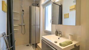Une salle de bain moderne avec une douche à parois de verre, un lavabo blanc avec une serviette et un grand miroir.