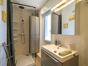 A modern bathroom with a glass-enclosed shower, a white sink with a towel, and a large mirror. - Studio 50m from the sea in Toulon (Toulon)