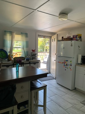 A kitchen with a white refrigerator, a wooden table, and a window with curtains.