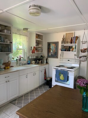 Une cuisine avec des meubles blancs, une cuisinière et divers ustensiles de cuisine.