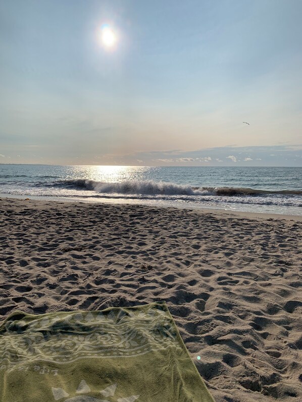 A beach with footprints, waves, and a clear sky.