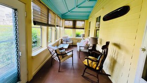 A sunroom with a wooden floor, a rocking chair, a sofa, and a table. - Historic 7-bedroom home in the heart of downtown in private setting,Pet friendly (New Shoreham)