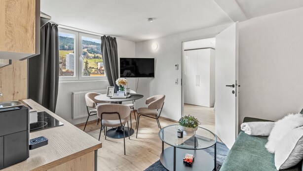 Ein modernes Zimmer mit Essbereich, Fernseher, Sofa und Blick auf die Stadt.