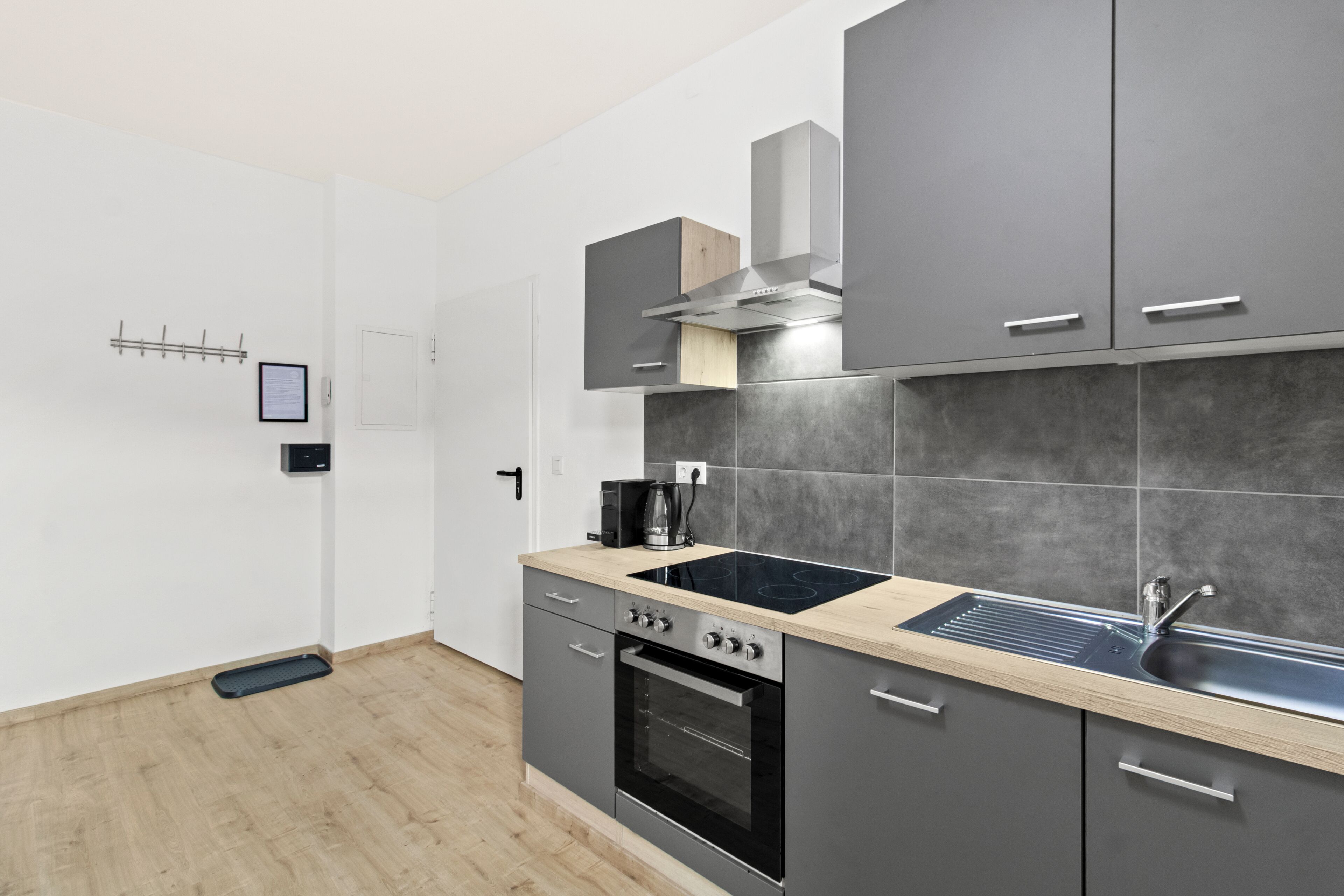 Une cuisine moderne avec des meubles gris, une cuisinière noire et un plan de travail en bois.