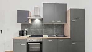 Eine moderne Küche mit grauen Schränken, einem Backofen, einer Kaffeemaschine und einem Spülbecken.