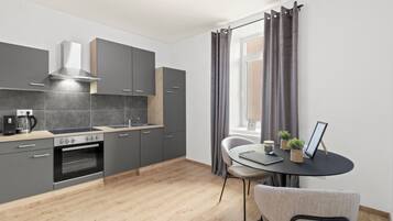 A modern kitchen with grey cabinets, a built-in oven, and a dining area with a round table and chairs.