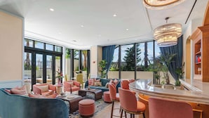 A modern lounge area with seating arrangements, a bar, and large windows offering views of the outdoors. - 1BR + Balcony | Skyline Spa | Walk to Wynwood Walls (Miami)