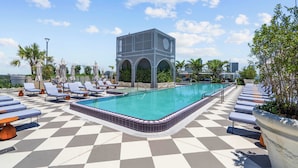 A rooftop pool area with lounge chairs, a swimming pool, and a modern building with arched windows. - 1BR + Balcony | Skyline Spa | Walk to Wynwood Walls (Miami)