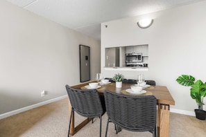 Comedor con mesa de madera, sillas tejidas negras y una pequeña planta en maceta.