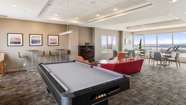 A modern indoor pool area with a pool table, seating, and large windows offering a view.
