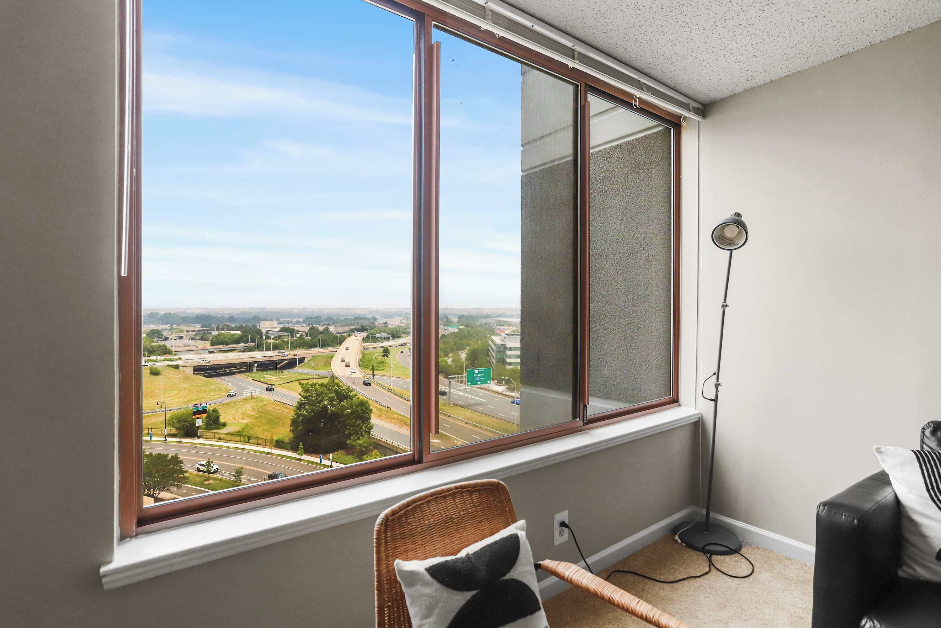 Una habitación con un ventanal grande que da a una autopista y al paisaje urbano.