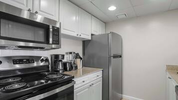 Una cocina moderna con electrodomésticos de acero inoxidable, armarios blancos y encimera de granito.