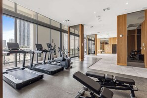 Ein modernes Fitnessstudio mit Laufbändern, Crosstrainern und Gewichtsbänken.