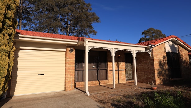 A residential building with a garage, a covered porch, and a brick exterior. - Spacious Three-bedroom Holiday Home With the Entire House Exclusively Yours (Sanctuary Point)