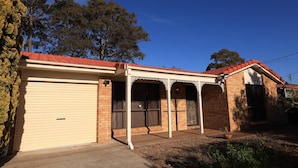 A single-story house with a garage, a covered porch, and a brick exterior. - Spacious Three-bedroom Holiday Home With the Entire House Exclusively Yours (Sanctuary Point)